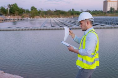 Yüzen güneş çiftliğinde çalışan Asyalı mühendis, yenilenebilir enerji, teknisyen ve yatırımcı güneş panelleri güneş enerjisi kurulumundaki panelleri kontrol ediyor