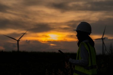Kadın mühendis, Tayland 'daki dağda rüzgar türbini tarım güç jeneratörü istasyonunda çalışıyor ve raporu tutuyor.