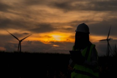 Kadın mühendis, Tayland 'daki dağda rüzgar türbini tarım güç jeneratörü istasyonunda çalışıyor ve raporu tutuyor.