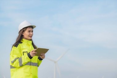 Kadın mühendis, Tayland 'daki dağda rüzgar türbini tarım güç jeneratörü istasyonunda çalışıyor ve raporu tutuyor.