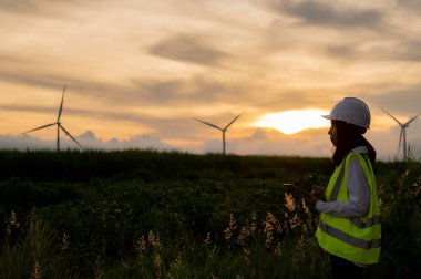 Kadın mühendis, Tayland 'daki dağda rüzgar türbini tarım güç jeneratörü istasyonunda çalışıyor ve raporu tutuyor.