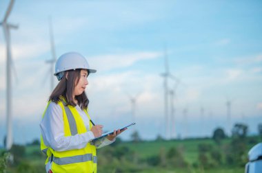 Kadın mühendis, Tayland 'daki dağda rüzgar türbini tarım güç jeneratörü istasyonunda çalışıyor ve raporu tutuyor.