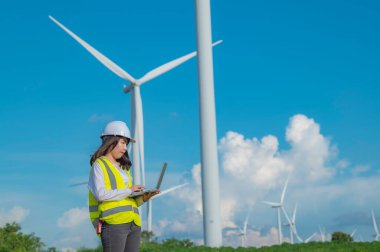 Kadın mühendis, Tayland 'daki dağda rüzgar türbini tarım güç jeneratörü istasyonunda çalışıyor ve raporu tutuyor.