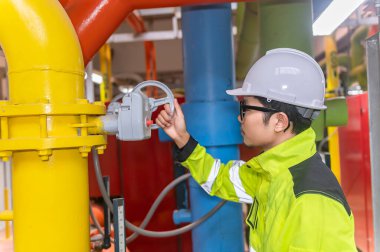 Kazan dairesinde çalışan gözlüklü Asyalı mühendis, ısıtma sistemi ekipmanlarının teknik verilerini kontrol ediyor, Taylandlılar