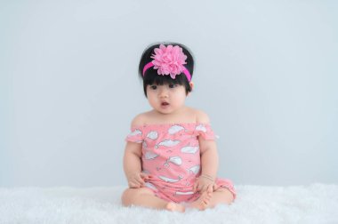 Beyaz halıdaki şirin Asyalı bebek portresi, fotoğraf çekmek için yeni doğan gülümsemesi.