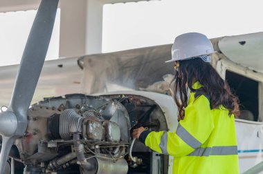 Teknisyen uçağın motorunu tamir ediyor, kadın uzay mühendisliği uçak motorlarını kontrol ediyor, Asyalı tamirci uçak motorlarını kontrol ediyor.