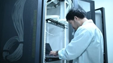 Computer engineer is setting up network in server room. Systems Maintenance Technician