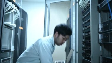 Computer engineer is setting up network in server room. Systems Maintenance Technician