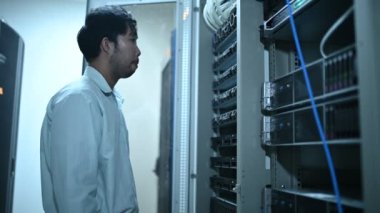 Computer engineer is setting up network in server room. Systems Maintenance Technician