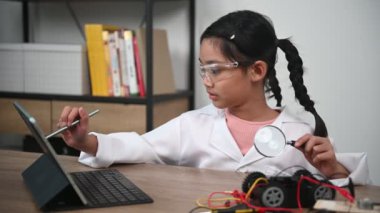 Asian little girl constructing and coding robot at STEM class. Fixing and repair mechanic toy car
