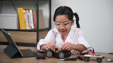 Asian little girl constructing and coding robot at STEM class. Fixing and repair mechanic toy car