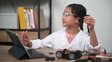 Asian little girl constructing and coding robot at STEM class. Fixing and repair mechanic toy car