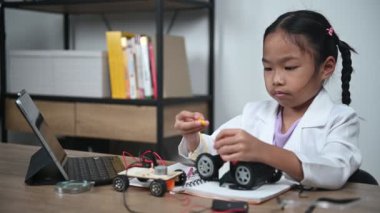 Asian little girl constructing and coding robot at STEM class. Fixing and repair mechanic toy car