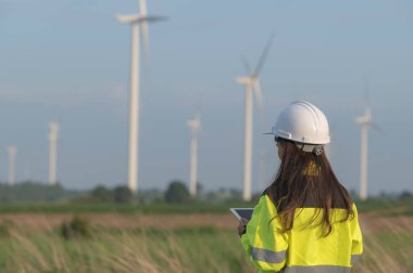 Kadın mühendis, Tayland 'daki dağda rüzgar türbini tarım güç jeneratörü istasyonunda çalışıyor ve raporu tutuyor.