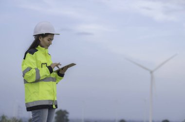 Kadın mühendis, Tayland 'daki dağda rüzgar türbini tarım güç jeneratörü istasyonunda çalışıyor ve raporu tutuyor.