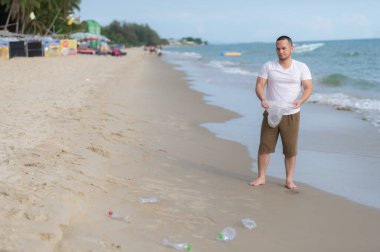 Asyalı adam çöpleri deniz sahilinde tutar, insanlar çöpleri plastik şişelerle saklamaya gönüllü olur.