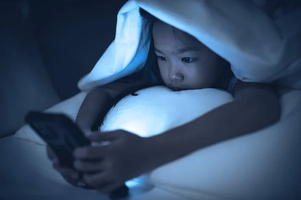 stock image Asian kid playing game on smartphone in the bed at night,The girl Addict social media