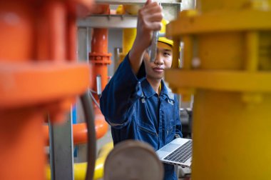 Bir ısıtma tesisinde bakım teknisyeni, Petrokimya işçileri fabrikadaki gaz ve petrol boru hatlarının işleyişini denetliyor, mühendisler işitme koruyucularını birçok boruyla aynı odaya koyuyorlar.
