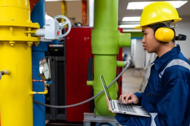 Bir ısıtma tesisinde bakım teknisyeni, Petrokimya işçileri fabrikadaki gaz ve petrol boru hatlarının işleyişini denetliyor, mühendisler işitme koruyucularını birçok boruyla aynı odaya koyuyorlar.
