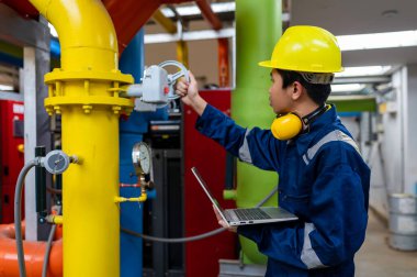 Bir ısıtma tesisinde bakım teknisyeni, Petrokimya işçileri fabrikadaki gaz ve petrol boru hatlarının işleyişini denetliyor, mühendisler işitme koruyucularını birçok boruyla aynı odaya koyuyorlar.