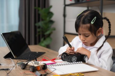 Küçük Asyalı kız STEM sınıfında robot yapıp kodluyor, mekanik oyuncak araba tamir ediyor ve tamir ediyor.
