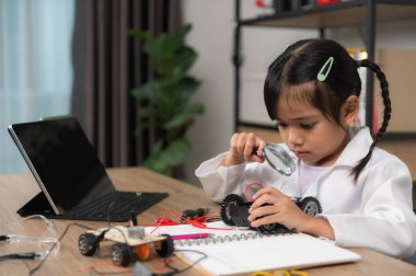 Küçük Asyalı kız STEM sınıfında robot yapıp kodluyor, mekanik oyuncak araba tamir ediyor ve tamir ediyor.