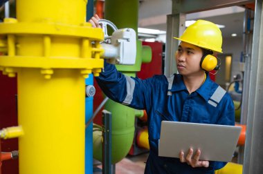 Bir ısıtma tesisinde bakım teknisyeni, Petrokimya işçileri fabrikadaki gaz ve petrol boru hatlarının işleyişini denetliyor, mühendisler işitme koruyucularını birçok boruyla aynı odaya koyuyorlar.