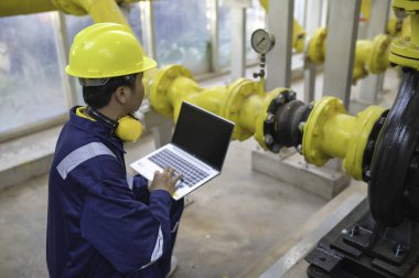 Bir ısıtma tesisinde bakım teknisyeni, Petrokimya işçileri fabrikadaki gaz ve petrol boru hatlarının işleyişini denetliyor, mühendisler işitme koruyucularını birçok boruyla aynı odaya koyuyorlar.