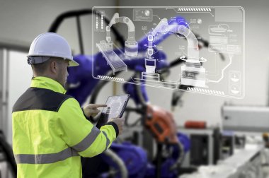 Genç Asyalı Mühendis Yöneticisi akıllı fabrika endüstrisinde otomasyon robot silah makinesini kontrol ediyor ve kontrol ediyor.