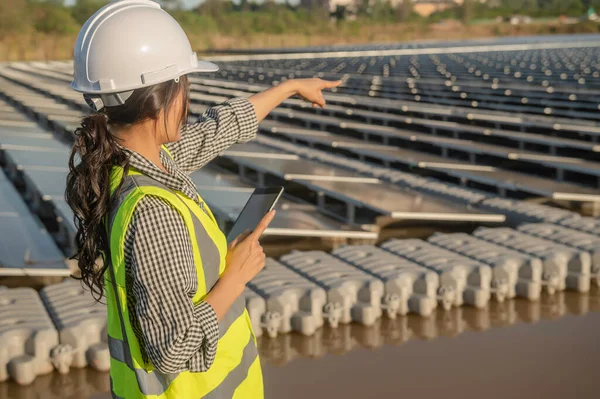 Yüzen güneş çiftliğinde çalışan Asyalı mühendis, yenilenebilir enerji, teknisyen ve yatırımcı güneş panelleri güneş enerjisi kurulumundaki panelleri kontrol ediyor