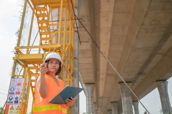 一名亚洲女工程师在高速公路桥梁建筑工地工作 负责检查过桥工程 — 图库照片