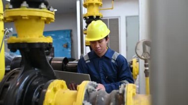Isıtma tesisinde bakım teknisyeni. Petrokimya işçisi fabrikadaki gaz ve petrol boru hatlarının işletilmesini denetliyor. Mühendis işitme koruyucuyu birçok boruyla aynı odaya koydu.