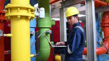 Isıtma tesisinde bakım teknisyeni. Petrokimya işçisi fabrikadaki gaz ve petrol boru hatlarının işletilmesini denetliyor. Mühendis işitme koruyucuyu birçok boruyla aynı odaya koydu.