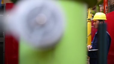 Isıtma tesisinde bakım teknisyeni. Petrokimya işçisi fabrikadaki gaz ve petrol boru hatlarının işletilmesini denetliyor. Mühendis işitme koruyucuyu birçok boruyla aynı odaya koydu.