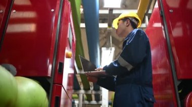 Isıtma tesisinde bakım teknisyeni. Petrokimya işçisi fabrikadaki gaz ve petrol boru hatlarının işletilmesini denetliyor. Mühendis işitme koruyucuyu birçok boruyla aynı odaya koydu.