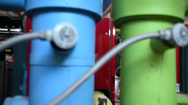 暖气厂的维修技术员 石油化工工人监督工厂内天然气和石油管道的运行 工程师把听觉保护装置放在有许多管子的房间里 — 图库视频影像