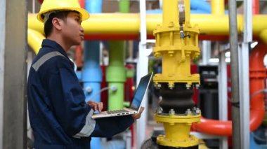 Isıtma tesisinde bakım teknisyeni. Petrokimya işçisi fabrikadaki gaz ve petrol boru hatlarının işletilmesini denetliyor. Mühendis işitme koruyucuyu birçok boruyla aynı odaya koydu.