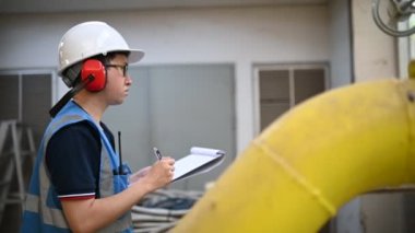 Isıtma tesisinde bakım teknisyeni. Petrokimya işçisi fabrikadaki gaz ve petrol boru hatlarının işletilmesini denetliyor. Mühendis işitme koruyucuyu birçok boruyla aynı odaya koydu.