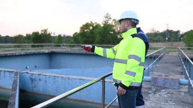 Çevre mühendisleri atık su arıtma tesislerinde, Su geri dönüşüm fabrikasında çalışan su mühendislerinde çalışıyor, teknisyenler ve mühendisler birlikte çalışmayı tartışıyor.