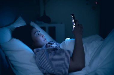 Asyalı kadın gece yatakta akıllı telefonla oyun oynuyor, Taylandlılar, sosyal medya bağımlısı.