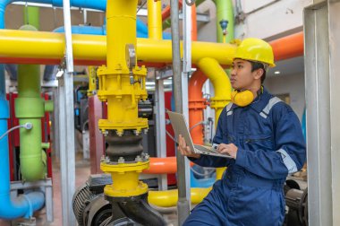 Bir ısıtma tesisinde bakım teknisyeni, Petrokimya işçileri fabrikadaki gaz ve petrol boru hatlarının işleyişini denetliyor, mühendisler işitme koruyucularını birçok boruyla aynı odaya koyuyorlar.