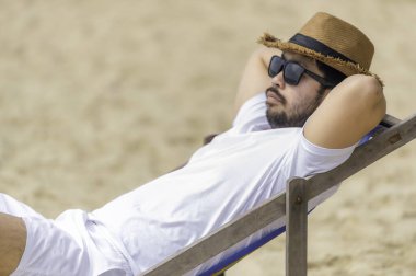 Asyalı bir adam denizin içinde sahilde oturuyor, Yazın dinlenme zamanı