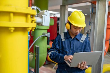 Bir ısıtma tesisinde bakım teknisyeni, Petrokimya işçileri fabrikadaki gaz ve petrol boru hatlarının işleyişini denetliyor, mühendisler işitme koruyucularını birçok boruyla aynı odaya koyuyorlar.