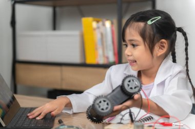 Küçük Asyalı kız STEM sınıfında robot yapıp kodluyor, mekanik oyuncak araba tamir ediyor ve tamir ediyor.