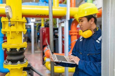 Bir ısıtma tesisinde bakım teknisyeni, Petrokimya işçileri fabrikadaki gaz ve petrol boru hatlarının işleyişini denetliyor, mühendisler işitme koruyucularını birçok boruyla aynı odaya koyuyorlar.