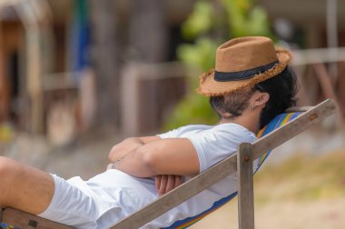 Asyalı bir adam denizin içinde sahilde oturuyor, Yazın dinlenme zamanı