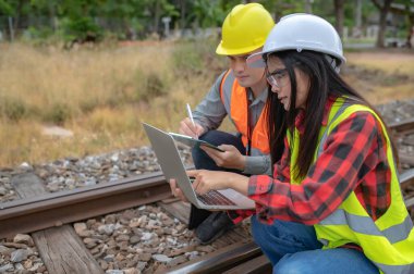 Tren istasyonunda çalışan iki mühendis, birlikte mutlu bir şekilde çalışıp, sorunu çözümlemede birbirlerine yardım edip, gelişim yönergelerine danışırlar.