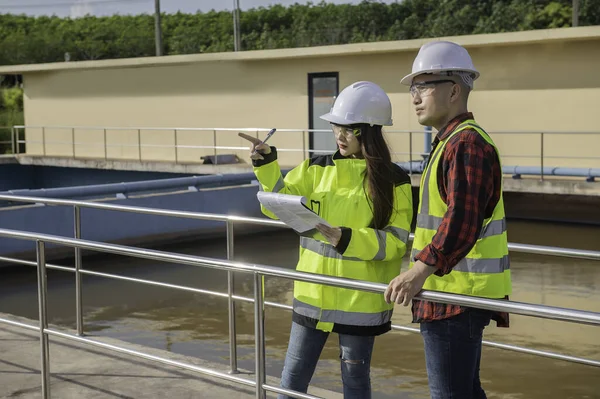 Çevre mühendisleri atık su arıtma tesislerinde, Su geri dönüşüm fabrikasında çalışan su mühendislerinde çalışıyor, teknisyenler ve mühendisler birlikte çalışmayı tartışıyor.