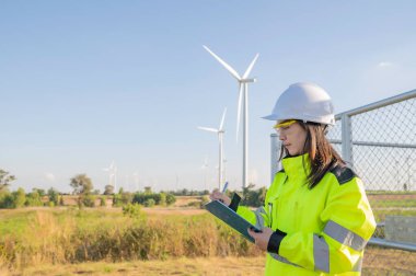 Taylandlı, dağdaki rüzgar türbini çiftliği güç jeneratörü istasyonunda çalışan Asyalı kadın mühendisler ve iş yerindeki teknisyenler.