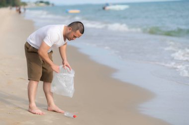 Asyalı adam çöpleri deniz sahilinde tutar, insanlar çöpleri plastik şişelerle saklamaya gönüllü olur.